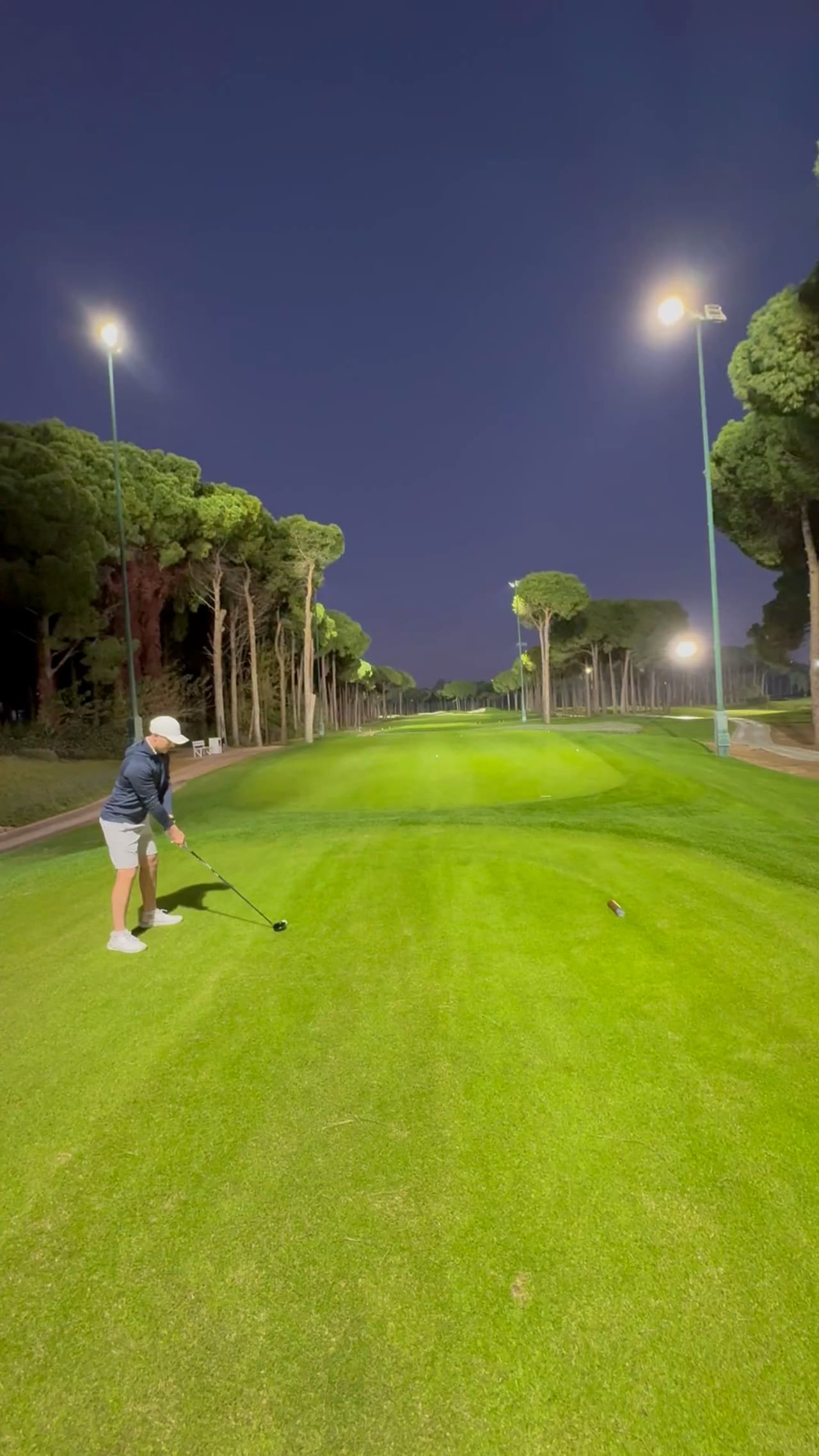 Huw Williams at address on a floodlit fairway at dusk